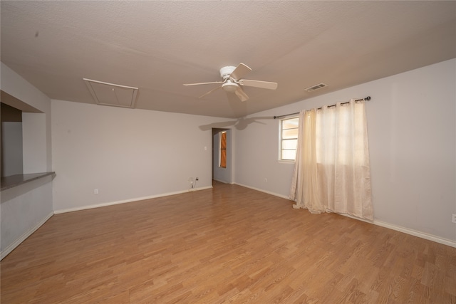 empty room with a textured ceiling, light wood-type flooring, and ceiling fan