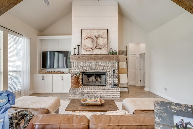 living room with a fireplace, high vaulted ceiling, and light hardwood / wood-style flooring