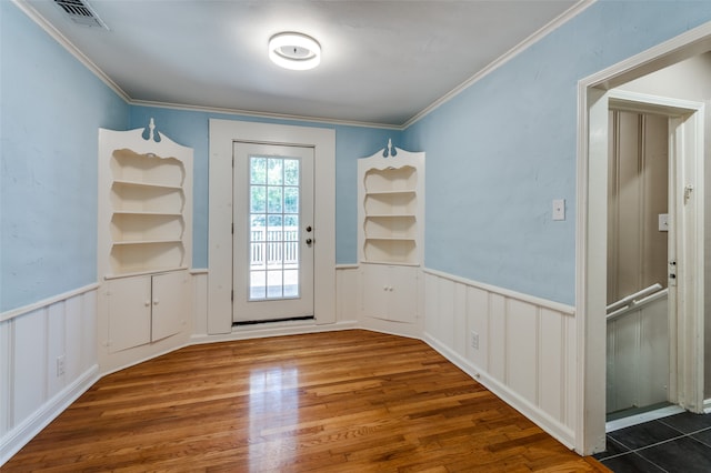 doorway featuring built in features, hardwood / wood-style floors, and crown molding