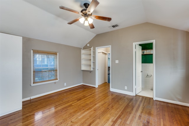 unfurnished bedroom featuring ceiling fan, connected bathroom, a walk in closet, a closet, and light wood-type flooring