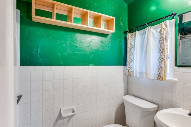 bathroom with tile walls and toilet