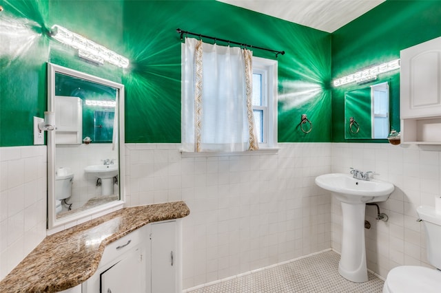 bathroom with tile walls, tile patterned flooring, toilet, and sink