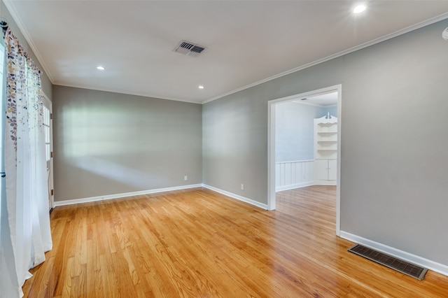 spare room featuring light wood-type flooring and crown molding