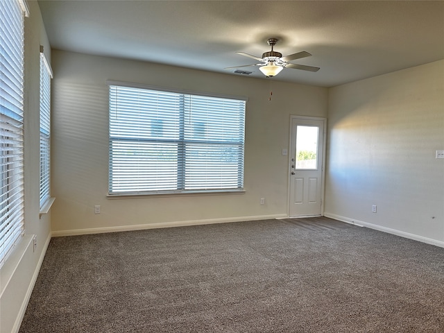 spare room featuring ceiling fan and dark carpet