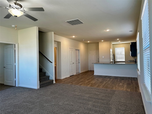 unfurnished living room featuring ceiling fan, dark hardwood / wood-style floors, and sink