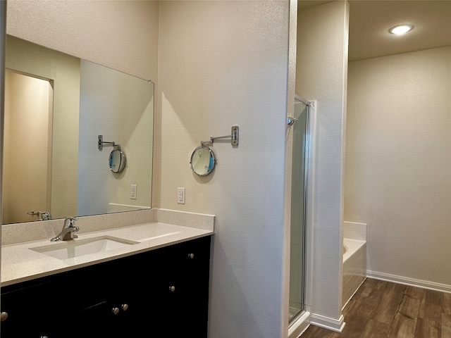 bathroom with hardwood / wood-style flooring, vanity, and separate shower and tub