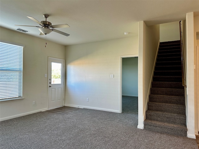 interior space with ceiling fan and dark carpet