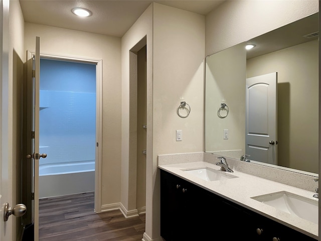 bathroom featuring wood-type flooring, a bath, and vanity