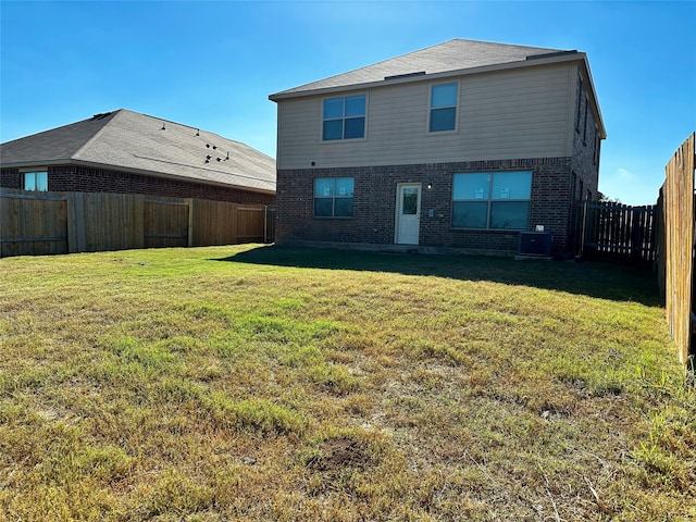 rear view of house featuring a lawn and central AC unit