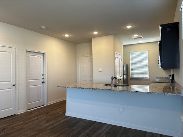 kitchen featuring kitchen peninsula, light stone countertops, stainless steel appliances, dark hardwood / wood-style floors, and sink