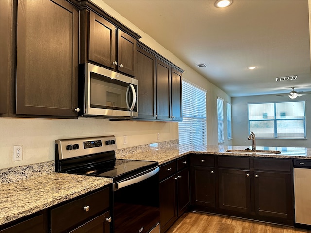 kitchen with ceiling fan, dark brown cabinetry, sink, stainless steel appliances, and light hardwood / wood-style floors