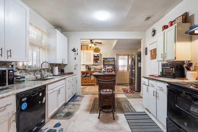 kitchen with black appliances, plenty of natural light, and white cabinets