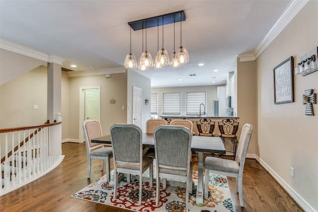 dining space featuring an inviting chandelier, crown molding, dark hardwood / wood-style floors, and ornate columns