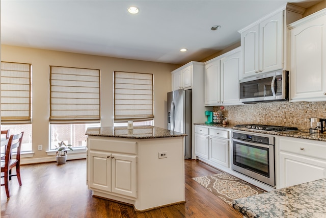 kitchen featuring dark stone countertops, hardwood / wood-style flooring, stainless steel appliances, and a center island