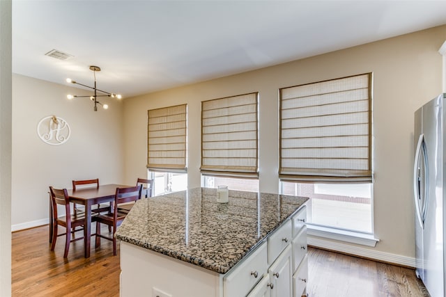 kitchen featuring light hardwood / wood-style floors, stainless steel fridge, plenty of natural light, and white cabinets