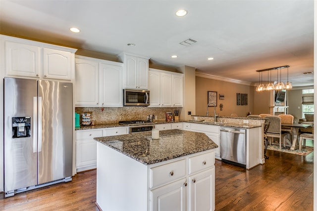 kitchen with kitchen peninsula, appliances with stainless steel finishes, sink, and dark hardwood / wood-style flooring