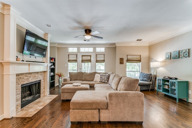 living room featuring a stone fireplace, ornamental molding, dark hardwood / wood-style floors, and ceiling fan