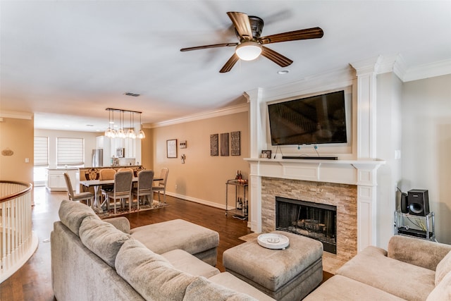 living room with a stone fireplace, hardwood / wood-style flooring, ceiling fan with notable chandelier, and ornamental molding