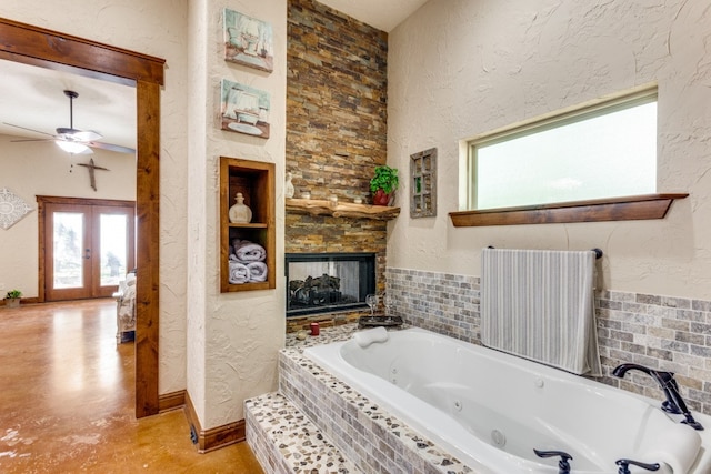 bathroom featuring tiled tub, a multi sided fireplace, ceiling fan, and french doors