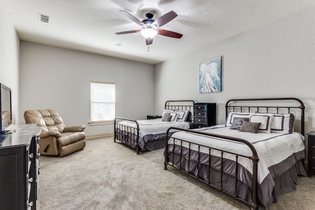 carpeted bedroom featuring ceiling fan and a textured ceiling