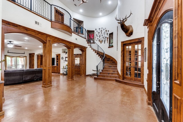 foyer entrance with a high ceiling, ceiling fan, concrete floors, and french doors