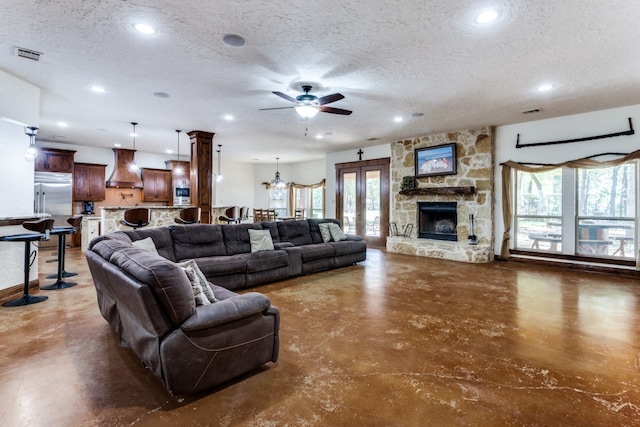 living room featuring a textured ceiling, a fireplace, and ceiling fan