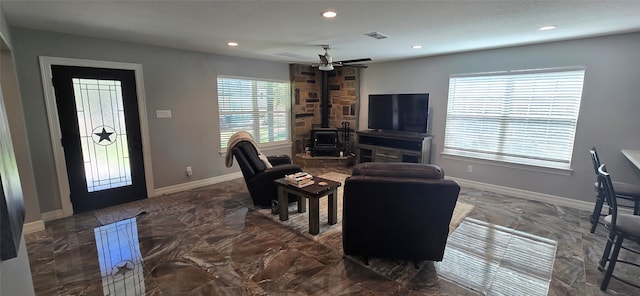 living room with a wood stove and ceiling fan