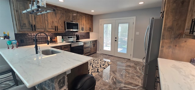 kitchen featuring sink, kitchen peninsula, french doors, stainless steel appliances, and a breakfast bar