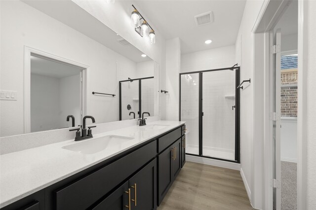 bathroom with wood-type flooring, vanity, and a shower with door