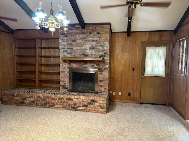 carpeted living room with lofted ceiling with beams, wood walls, ceiling fan with notable chandelier, and a fireplace