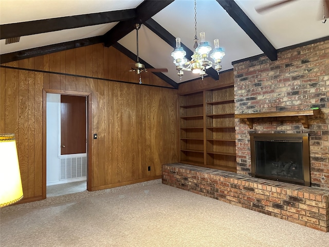 unfurnished living room featuring lofted ceiling with beams, a chandelier, wood walls, carpet floors, and a fireplace