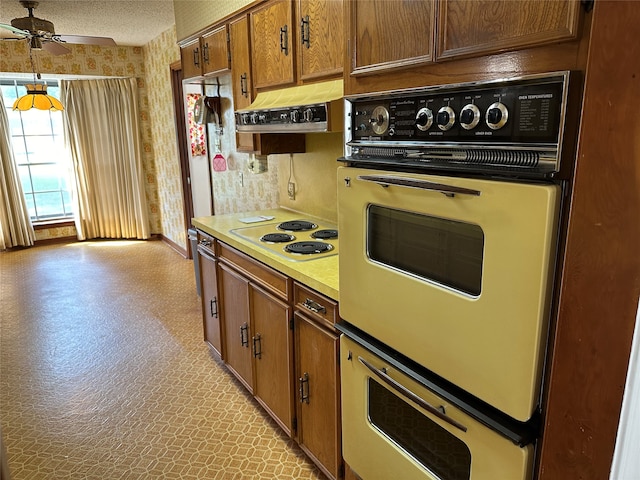 kitchen with ceiling fan, black oven, a textured ceiling, and white electric cooktop