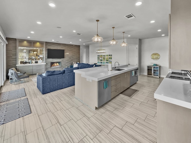 kitchen with pendant lighting, a large fireplace, a large island with sink, and sink