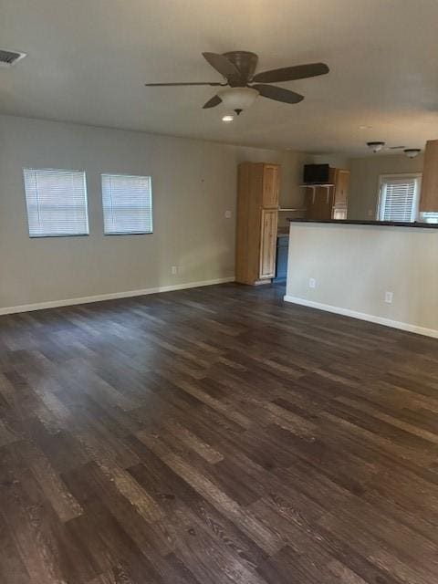 unfurnished living room with ceiling fan and dark wood-type flooring