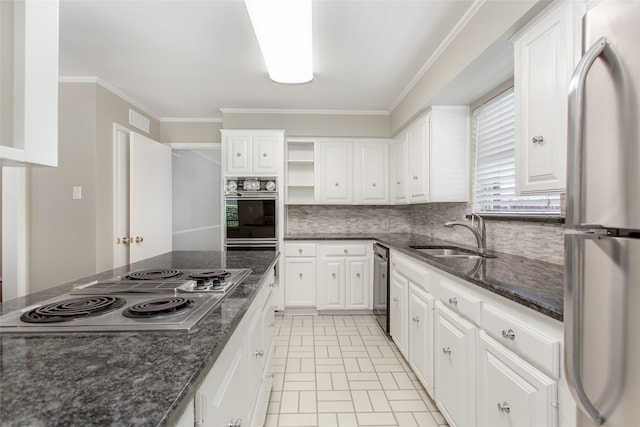 kitchen with dark stone counters, stainless steel appliances, white cabinetry, and sink