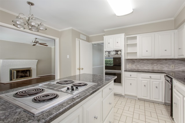 kitchen featuring white cabinets, ceiling fan with notable chandelier, a fireplace, black double oven, and white electric stovetop