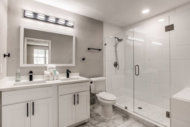 bathroom with a textured ceiling, vanity, toilet, and a shower with shower door