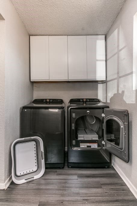 clothes washing area featuring cabinets, a textured ceiling, washing machine and dryer, and hardwood / wood-style flooring