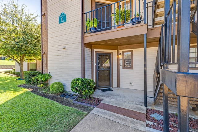 doorway to property with a balcony and a lawn