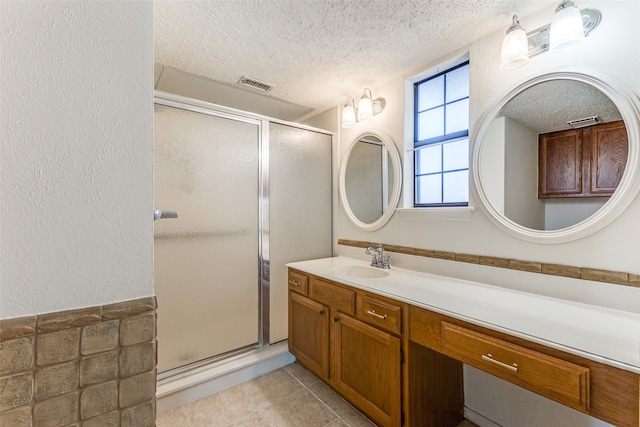 bathroom with a textured ceiling, vanity, and walk in shower