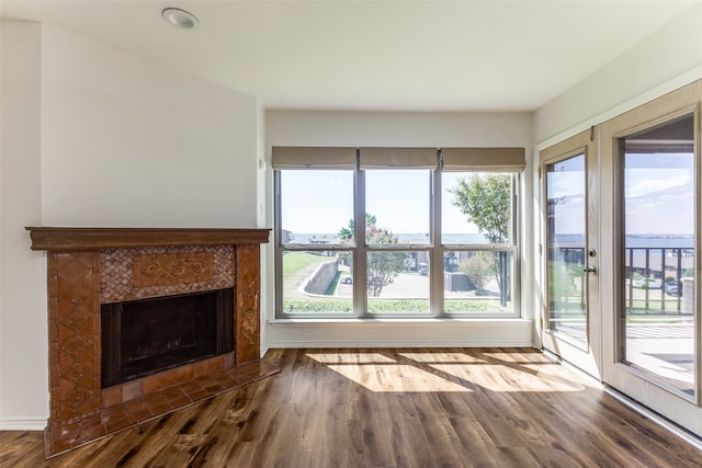 unfurnished living room featuring hardwood / wood-style flooring, a tiled fireplace, and a wealth of natural light