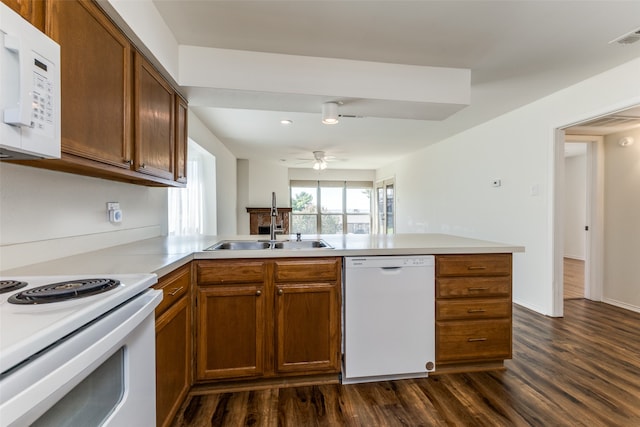 kitchen featuring white appliances, kitchen peninsula, dark wood-type flooring, and sink