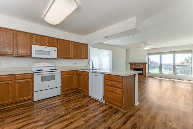 kitchen with dark wood-type flooring, sink, kitchen peninsula, white appliances, and ceiling fan