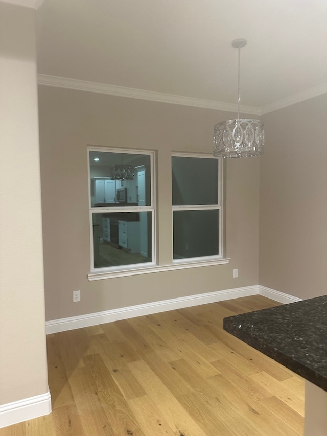 unfurnished dining area with crown molding, hardwood / wood-style floors, and a notable chandelier