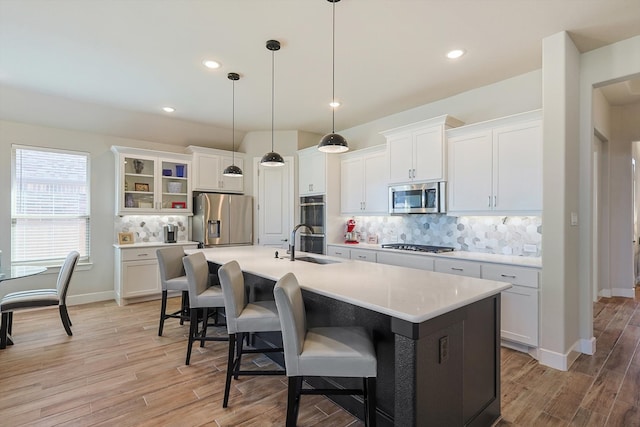 kitchen with an island with sink, white cabinets, stainless steel appliances, and light hardwood / wood-style floors