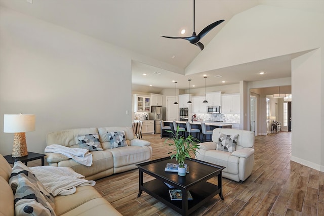 living room with hardwood / wood-style flooring, ceiling fan, and high vaulted ceiling