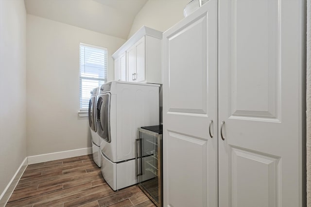 clothes washing area with washing machine and dryer, wine cooler, cabinets, and dark hardwood / wood-style floors