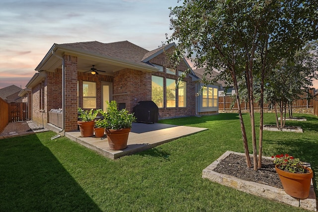 yard at dusk with ceiling fan and a patio