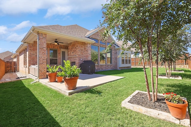 back of house featuring a lawn, ceiling fan, and a patio area