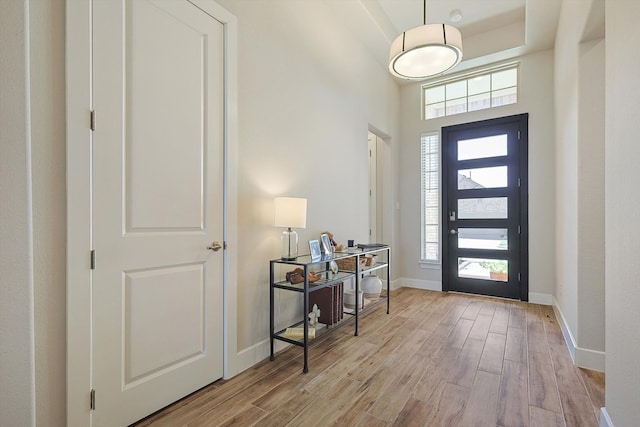 entrance foyer with light wood-type flooring and a towering ceiling